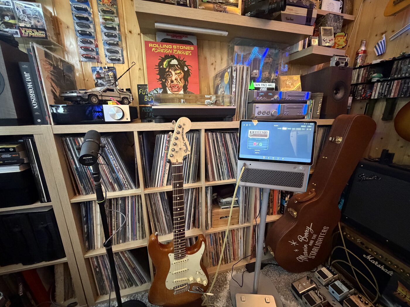 A Stratocaster and turntable in front of shelves of vinyl